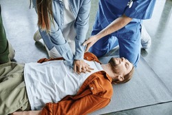 cardiopulmonary resuscitation, professional instructor helping woman practicing chest compressions on young man lying in training room, effective life-saving skills and techniques concept