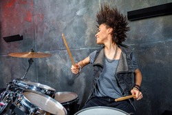 portrait of emotional woman playing drums in studio, drummer rock concept