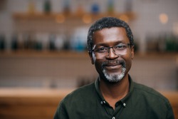 happy african american mature man in front of blurred bar counter