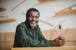 smiling mature african american man sitting in cafe and looking at camera