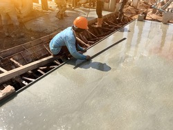 man hand spreading concrete mix with trowel in foundation. A construction worker is pouring cement and concrete,Selective focus.