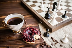 Tea break with board games. Coffee cup with fresh coffee and snacked donat