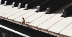 Miniature figurine of a woman sitting and reading on the keys of a piano.