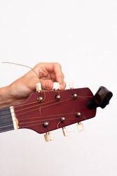 Guitar tuner. Wooden guitar on a white background. Guitar tuning. The guy tunes the guitar.