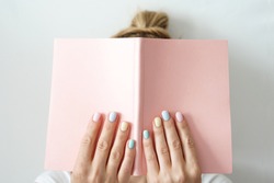 Stylish trendy color female manicure . Woman’s hands keep pink note pad