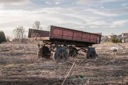 Empty wagon in field, agriculture machine. Old empty farming cart, abandoned place