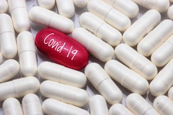 view a red pill word - COVID-19 with many white pills, close up. Medical concept of Virus Pandemic Protection, Coronavirus COVID-19


