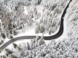 Empty road, no cars, restricted traffic due to the pandemic situation. Winding road from high mountain pass, in winter time. Aerial view by drone.