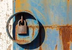A rusty padlock on a rusty metal door