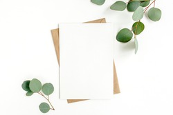 Mockup invitation, blank greeting card and green leaves eucalyptus. Flat lay, top view.