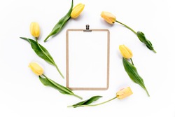 Clipboard mock up with beautiful yellow tulips isolated on white background. Flat lay, top view. Minimalistic office desk. Beauty blog concept.