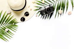 Traveler accessories, tropical palm leaf branches on white background with empty space for text. Travel vacation concept. Summer background. Road frame set. Flat lay, top view.