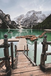 Scenic view of boats tethered on floating pier of Lake Braies (germ. Pragser Wildsee, ital. Lago di Braies) boathouse in Italy against cloudy sky