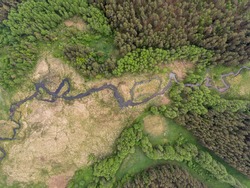 Aerial view over Latazeris lake with a curvy river stream from the forest near the border, Lithuania. During cloudy summer day.