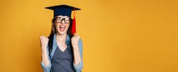 Study, education, university, college, graduate concept on yellow banner. Happy and excited portrait of young blond student girl in hat of graduation isolated 