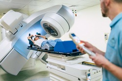 Cancer treatment in a modern medical private clinic or hospital with a linear accelerator. Professional doctors team working while the woman is undergoing radiation therapy for cancer
