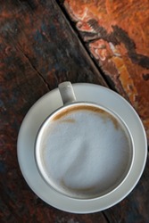 White cup of cappuccino coffee on wooden tabletop, close up. Copy space.