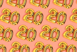 Numbers 20 golden balloons pattern. Twenty years anniversary celebration layout on a coral background.
