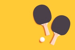 Tennis rackets and white ball on a yellow background. Ping pong concept.