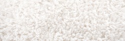 Background picture of a soft fur white carpet. wool sheep fleece closeup texture background. Fake color beige fur fabric. top view.  banner size. panorama. ,panoramic.