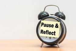 Written pause  reflect with paper on alarm clock.
Pause and reflect word with time concept.