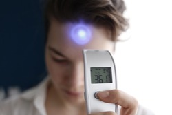 A female person being measured body temperature with a contactless thermometer
