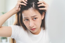 Hair loss problem, Asian woman look at scalp worry about balding.