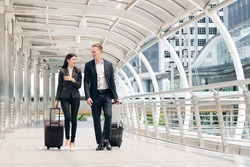 Businessman and businesswoman talking and hold luggage travel to business trip.