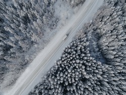 Aerial view on road in winter time, road surrounded with forest trees, car driving in winter time. Rural winter area