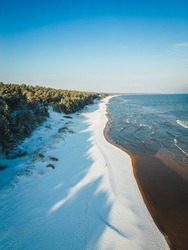 Aerial view on beautiful Baltic sea shore by the pine forest in winter season, winter landscape