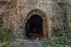 Military underground ruined brick tunnel entrance. Dark hole of subterranean grotto exit