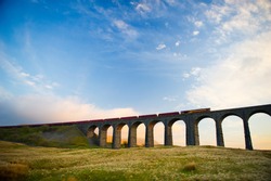 Train crosses the famous Ribblehead Viaduct. The Ribblehead Viaduct or Batty Moss Viaduct carries the Settle–Carlisle Railway across Batty Moss in the valley of the River Ribble at Ribblehead.