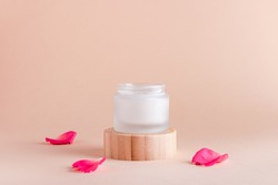 Facial cream with rose extract and rose petals in minimal still life.