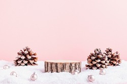 Wooden podium or platform on pastel pink background for cosmetic product mockup with natural cedar pine cones