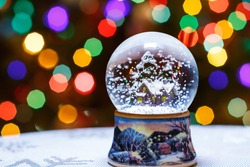 Christmas Snow Globe in front of Christmas tree lights closeup, blurred background