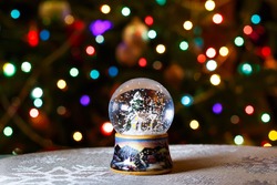 Christmas Snow Globe in front of Christmas tree lights closeup, blurred background
