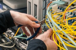 Cable cutters in the hands of an internet connection installer. The specialist removes unnecessary wires in the data center.Cutting fiber in the server room.