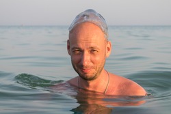 The man was hit on the head by a large jellyfish. Funny situation. Portrait of a guy with a jellyfish on his head in the sea.