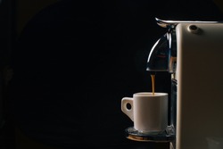 Coffee machine with capsule. Pouring coffee espresso over dark background, free copy space for your text