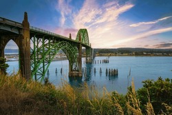 Sunset over Yaquina Bay Bridge in Newport, Oregon. The Yaquina Bay Bridge is an elegant art deco structure arching over the picturesque bay.