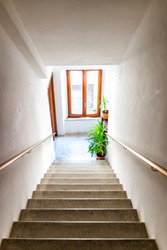 Vertical view of hall interior in Italian apartment home with window and green plants looking down high angle above steps stairs in hallway