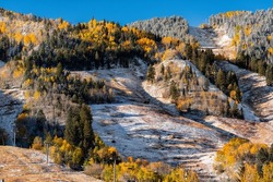 Aspen, Colorado buttermilk highlands ski slope hill peak in rocky mountains on sunny day with snow on yellow foliage autumn or winter trees closeup