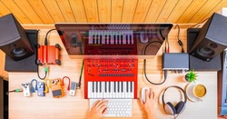 top view of professional music producer, composer hands arranging music on computer and recording equipments on desk. music production technology, home studio, e-learning concept