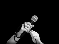 black and white microphone in male singer hands, isolated on black. music background
