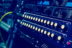 recording studio gears in rack, focus on knob & shallow dept of field. cross processed filter