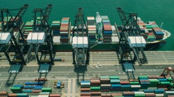 Freight being unloaded from ships. Shipping containers on dock. Aerial view