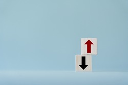Up and down turn arrow on wooden blocks difference direction to earn or to loss. Red arrow as positive and black as negative movement idea.