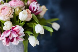 
Flower arrangement with tulips and ranunculus on a white wooden floor. Spring flower arrangement in a vase