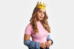One Young Indian Asian cheerful attractive brunette hair woman with Golden Crown on her head is standing isolated on a white background screen. Self-love, success, achievement, leadership concept.