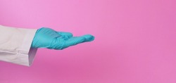 Empty Hand wear doctor gown and blue glove on pink background. Do begging Studio shooting.